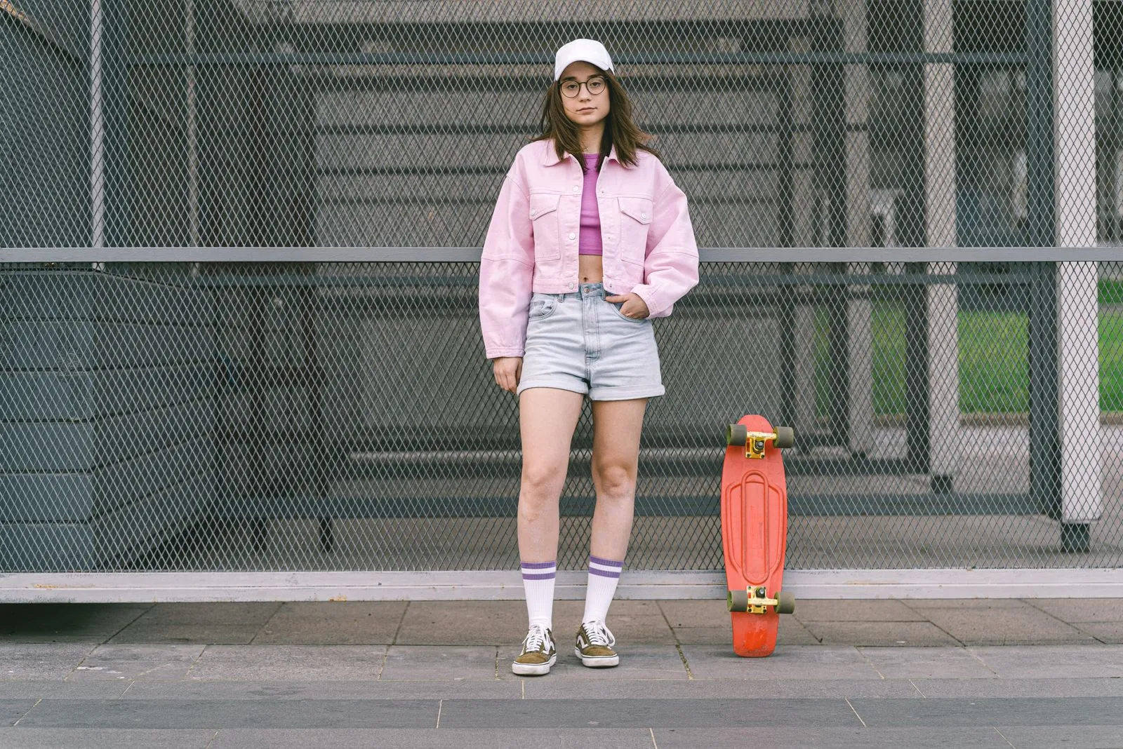 Young woman in casual outfit posing with a skateboard in an urban setting.